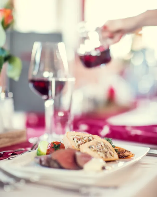 Gourmet beef dish with stuffed pastry and red wine served on an elegant table setting